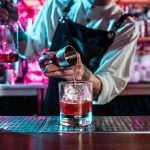 Expert barman is making cocktail at night club.